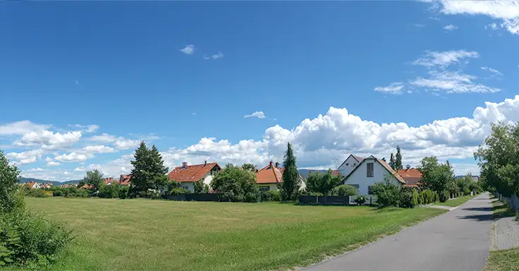 Grüne Wiese mit Einfamilienhäusern und blauem Himmel
